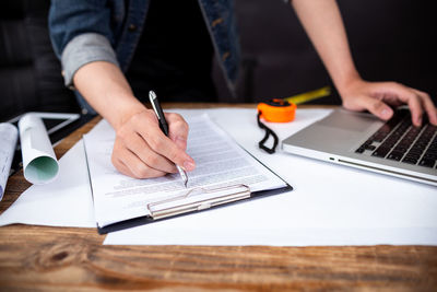 Midsection of man using mobile phone on table