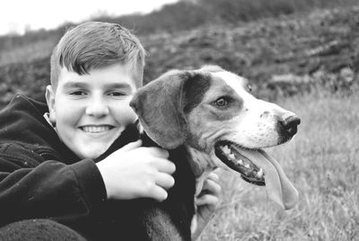 Portrait of boy with dog sitting on field