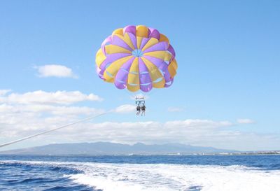 Man and woman paragliding over sea against sky