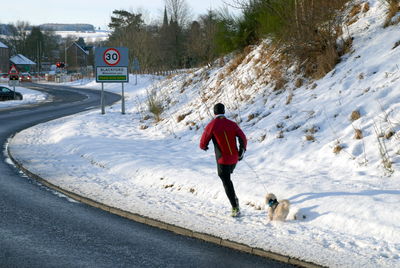 Rear view of man with dog on snow