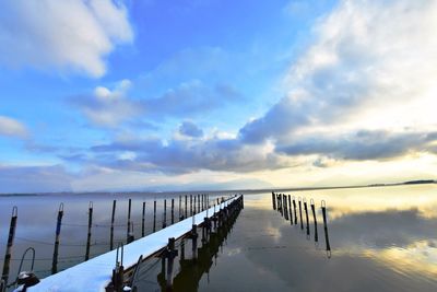 Wooden posts in sea against sky