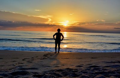 Silhouette man on beach against sky during sunset