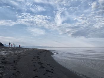 View of people standing on beach against sky