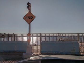 Road sign by sea against clear sky