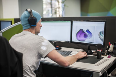 Young man wearing headphones working on computer in office