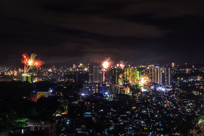 High angle view of illuminated cityscape against sky and fireworks at night