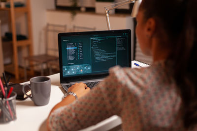 Midsection of woman using laptop on table