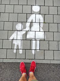 Low section of man standing by pedestrian sign on paving footpath