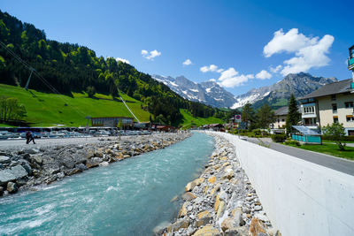 Scenic view of river by mountains against sky