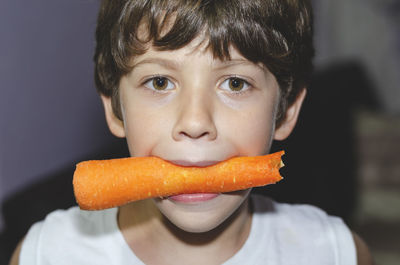 Happy little boy eating a fresh carrot and having fun. healthy vegetarian food. at home. 