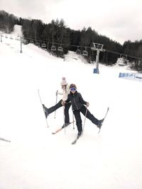 People skiing on snow field against sky