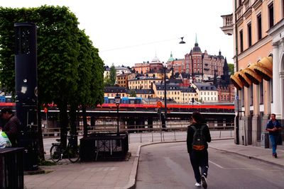 People walking on street by building against clear sky