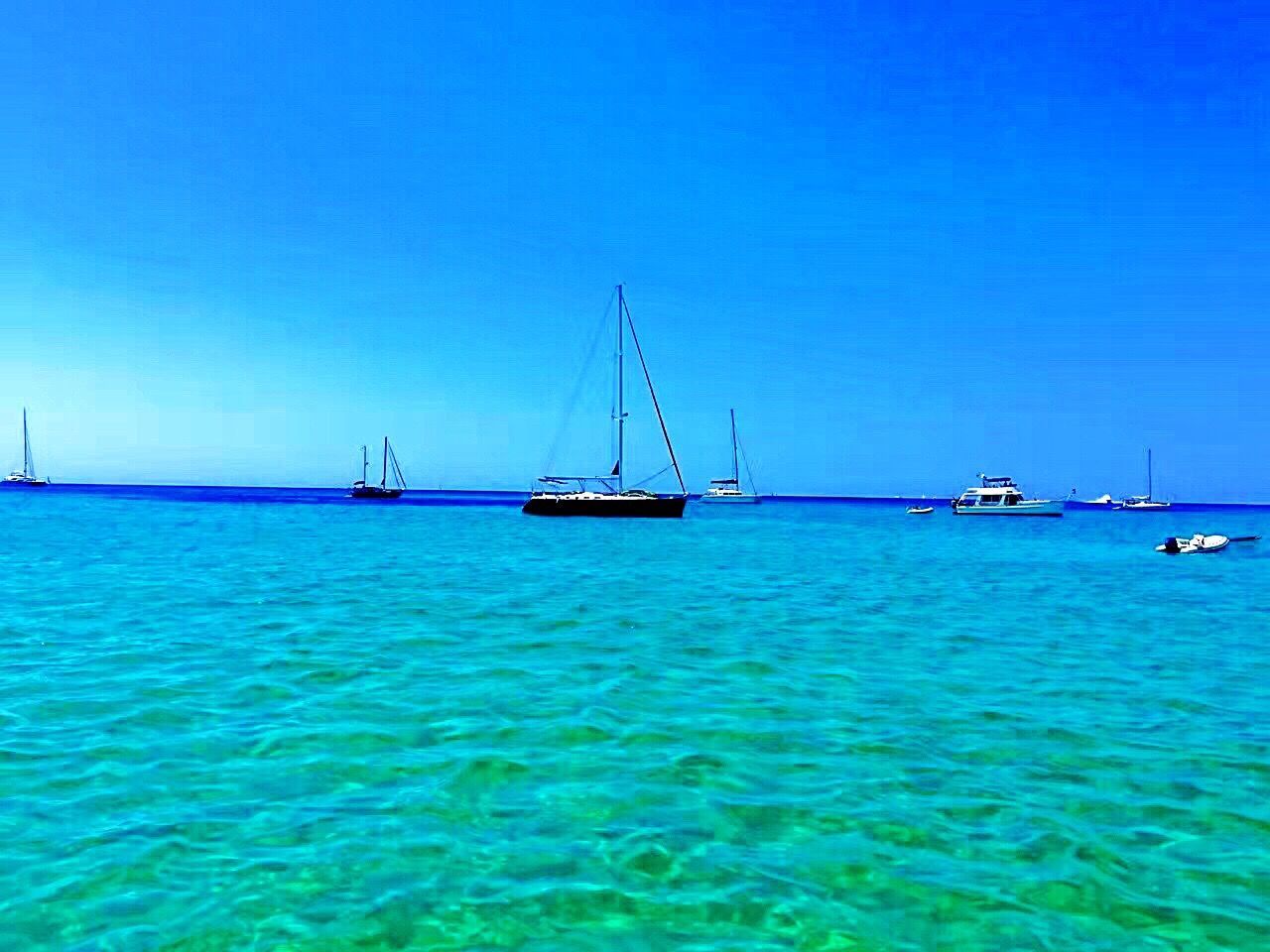 nautical vessel, transportation, blue, water, sea, mode of transport, boat, sailboat, clear sky, tranquil scene, scenics, waterfront, mast, tranquility, sailing, seascape, nature, journey, non-urban scene, ocean, beauty in nature, tourism, distant, vibrant color, no people, vacations