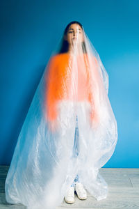 Woman covered in plastic standing against blue background