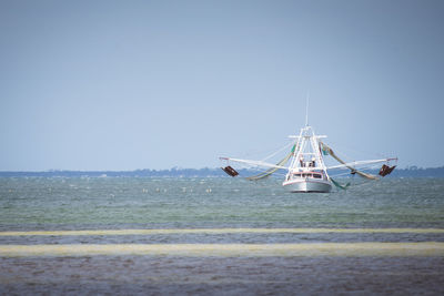 Ship sailing on ocean against clear sky