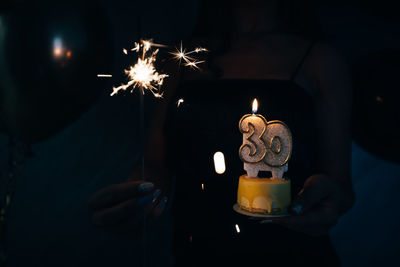 Close-up of illuminated burning candles in the dark