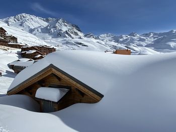 Snow covered houses and mountains against sky