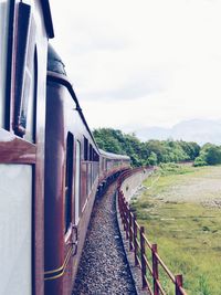 Diminishing view of train by field against sky