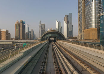 Railroad tracks amidst buildings in city against sky