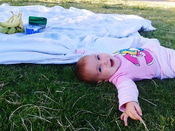 Portrait of cute girl lying on grassy field