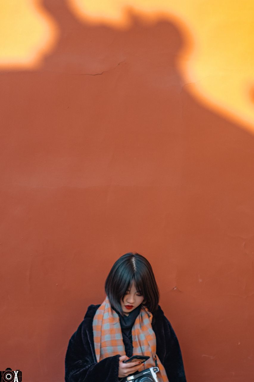 PORTRAIT OF YOUNG WOMAN STANDING AGAINST ORANGE SKY