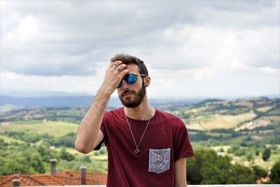 Portrait of man in sunglasses standing against landscape