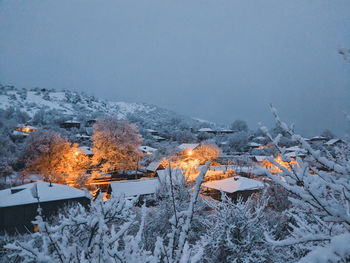 High angle view of snow covered trees and buildings against sky