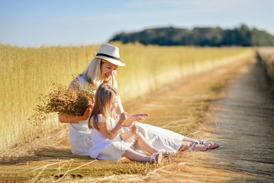 Rear view of woman sitting on field