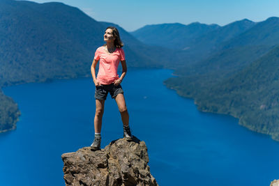 Hiker girl is on top of the mountain overlooking deep blue lake