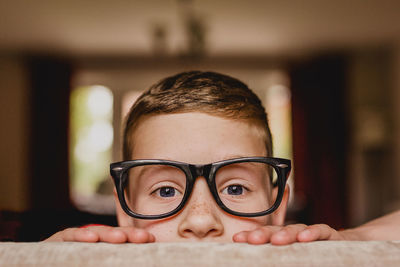 Portrait of peeking boy wearing oversized glasses