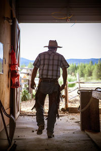 Rear view of man wearing cowboy hat at farm