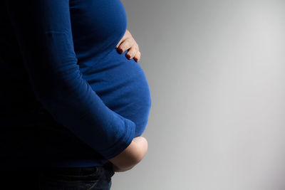 Midsection of woman standing against blue wall