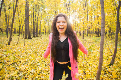 Smiling young woman standing in forest during autumn