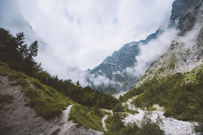 Scenic view of waterfall by mountains against sky