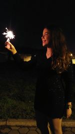 Side view of young woman standing at night