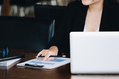 Midsection of woman using laptop at table