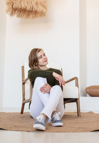 Young woman sitting on chair at home