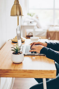 Midsection of woman using laptop on table