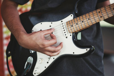 Midsection of man playing guitar