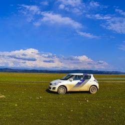 Car parked on field against sky