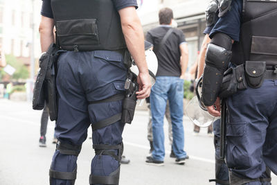 Rear view of police force standing on road in city