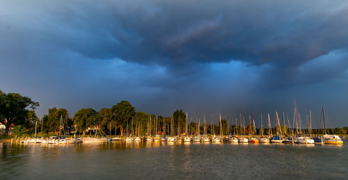 Sailboats moored on sea against sky at dusk