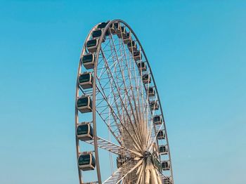 Low angle view of ferris wheel against clear blue sky