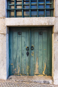 Antique low doors with peeling green paint