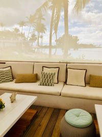 Chairs and table on sofa by palm trees