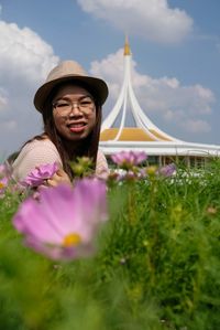 Portrait of woman with pink flowers against sky