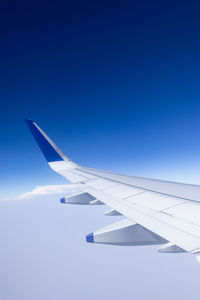 Cropped image of airplane wing against clear blue sky