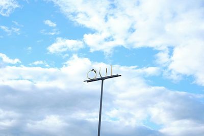 Low angle view of sign on pole against cloudy sky