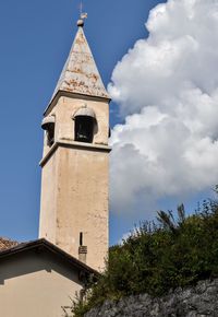 Low angle view of tower by building against sky