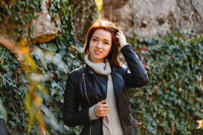 Beautiful young woman with light brown hair in a gray sweater and black leather